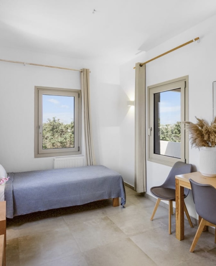 Light-filled room with single bed and desk by the balcony door