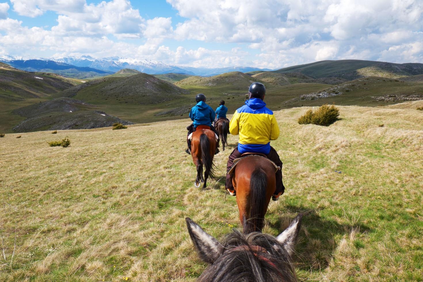 POV from horseback following riders across the open Mavrovo highlands toward snow-capped peaks