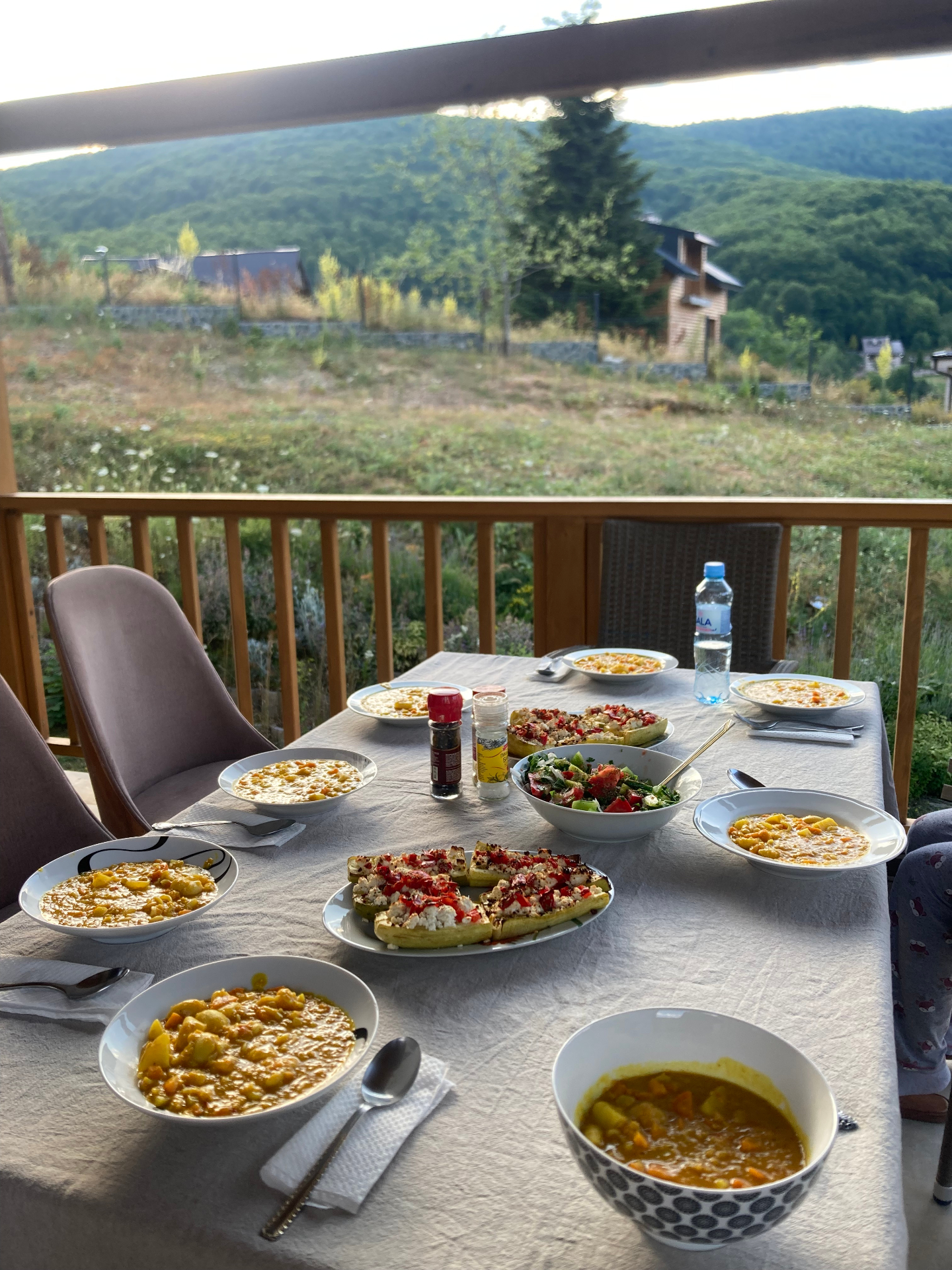 Long table set with bean stew, salads and roasted vegetables