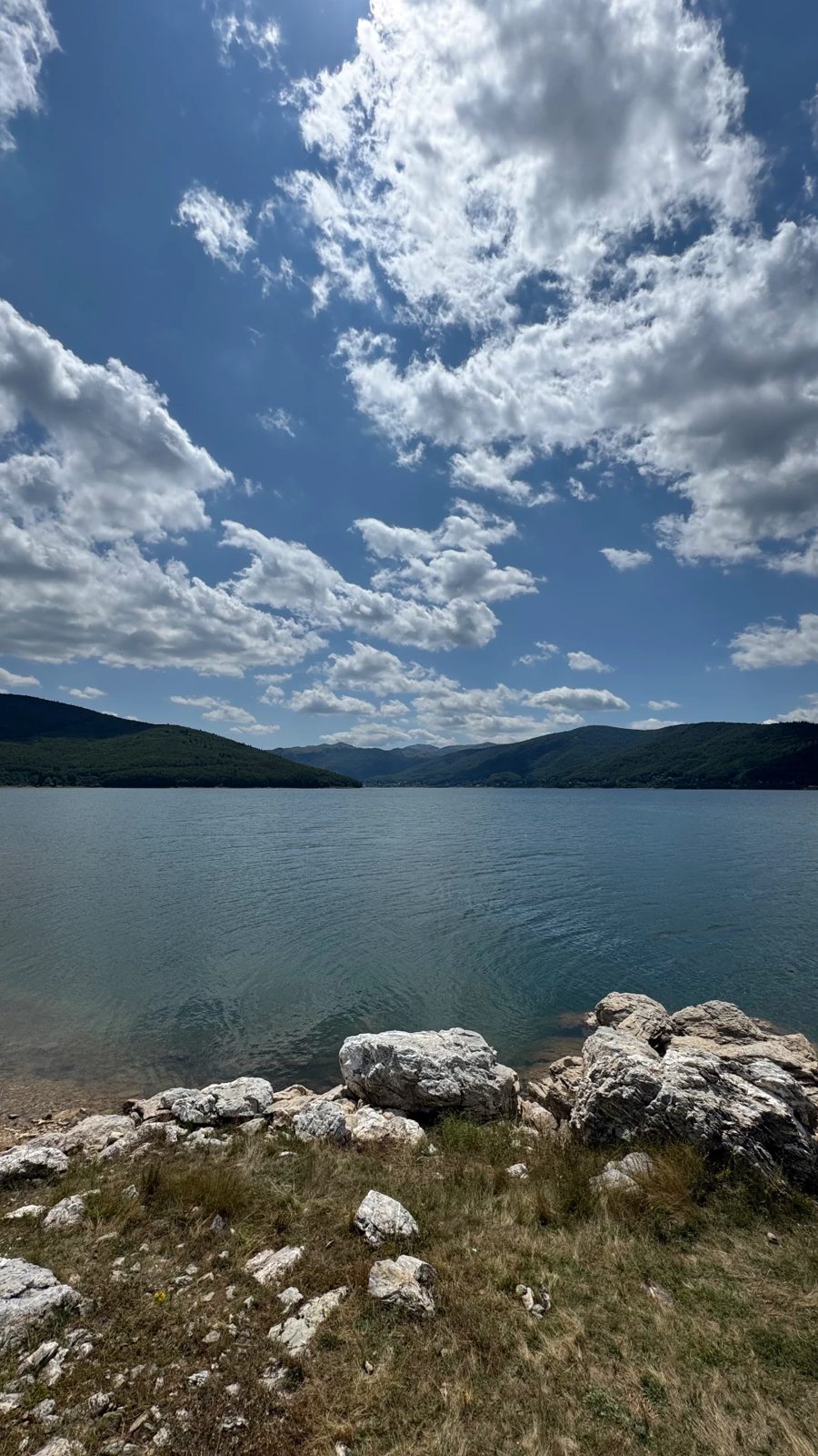 Lake Mavrovo shoreline under big summer clouds