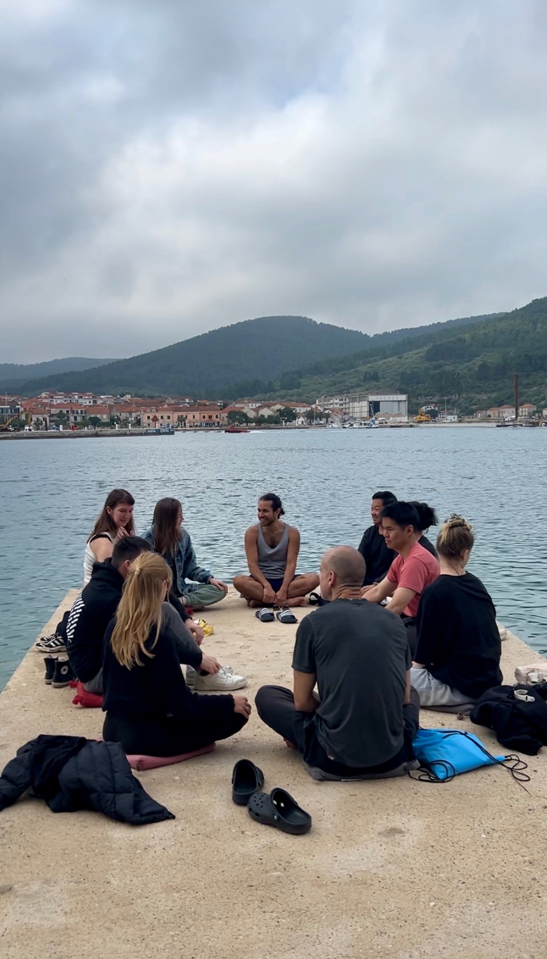 Group sitting in circle on the dock by the sea
